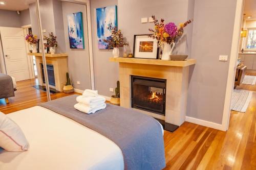 a living room with a fireplace and a bed at Fig Tree Luxury Guest House in Pokolbin
