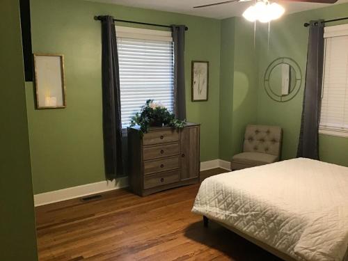 a bedroom with green walls and a bed and a dresser at Cute 2 bedroom house in Augusta in Augusta