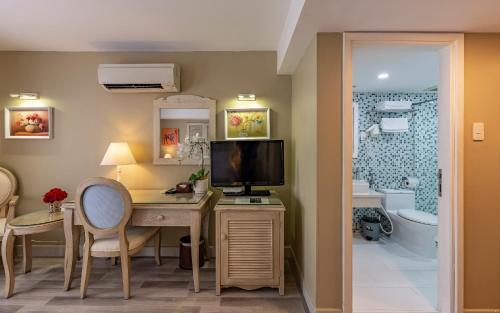 a room with a desk with a television and a bathroom at Hotel L Odeon Phu My Hung in Ho Chi Minh City