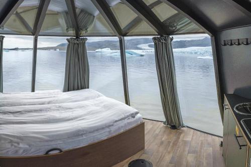 a bed in the back of a boat with a view of the water at Fjallsarlon - Overnight adventure in Hnappavellir