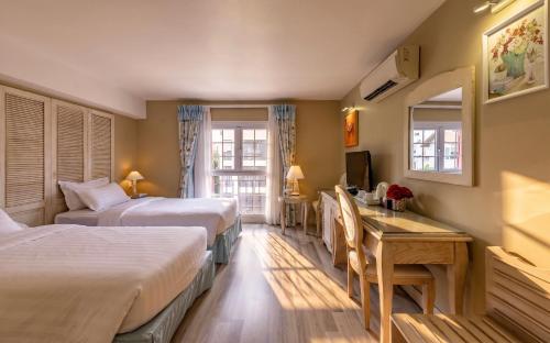 a hotel room with two beds and a desk at Hotel L Odeon Phu My Hung in Ho Chi Minh City