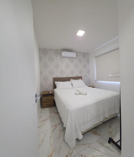 a bedroom with a white bed and a window at Apartamento Crisalidas em Foz in Foz do Iguaçu
