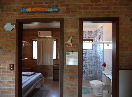 a room with a brick wall and a bathroom with a bed at Lumar Flats in Paulista