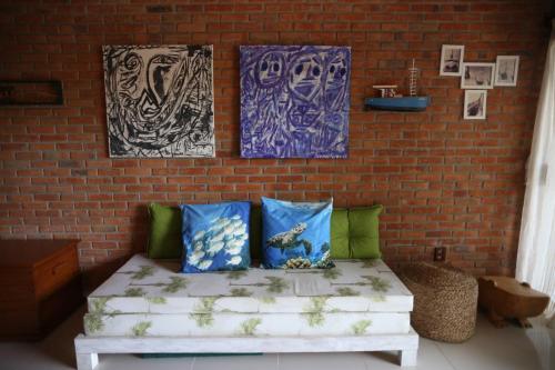 a living room with a couch and paintings on a brick wall at Lumar Flats in Paulista