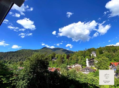 a village in the mountains with a blue sky and clouds at Panorama-Glück I & III in Garmisch-Partenkirchen