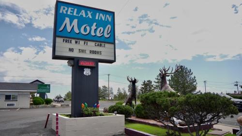 a motel sign in a parking lot with deer statues at Relax Inn in Flagstaff