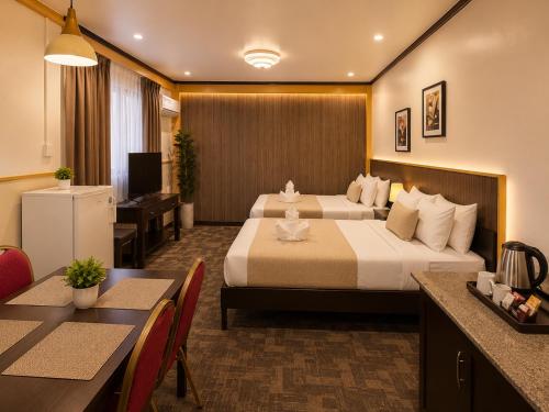 a hotel room with two beds and a table and chairs at Amax Inn Makati in Manila