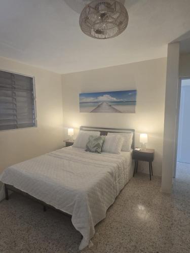a white bedroom with a large bed with two lamps at Casa Brisa Beach House in Dorado
