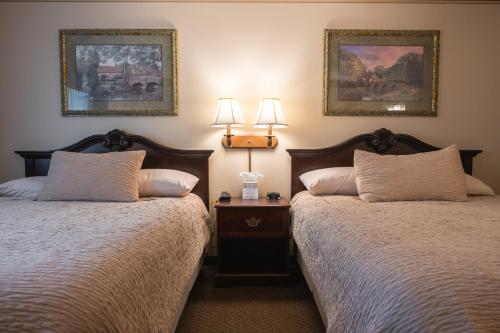 two beds in a room with two lamps on the wall at Hearthstone Inn & Suites in Cedarville