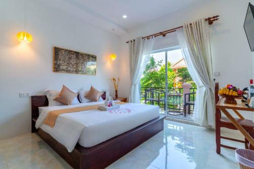 a bedroom with a large bed and a balcony at Angkor Rithy Residence 2 in Phumĭ Réach Born (1)