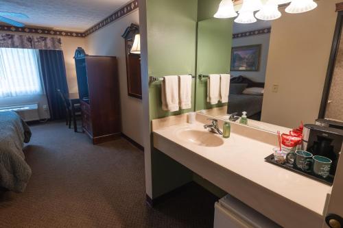 a bathroom with a sink and a bed and a mirror at Hearthstone Inn & Suites in Cedarville
