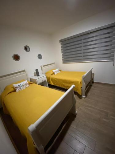 two beds in a room with yellow at AdHeDiLe & GIACAHER in Guadalupe