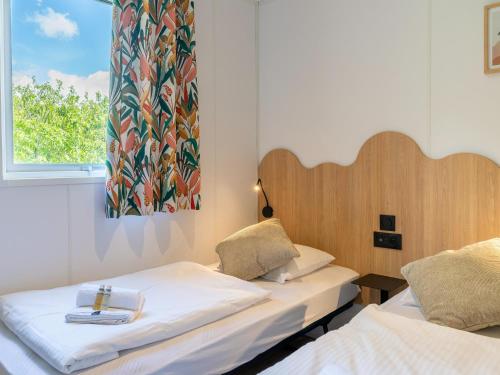 two beds in a room with a window at New Vennepark caravan 463 6p in De Haan