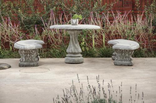 a concrete table and two stools in a garden at Olive Manor Guest House in Newcastle