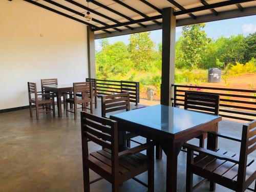a dining room with tables and chairs and a large window at wild elephant reach wilpattu in Nochchiyagama