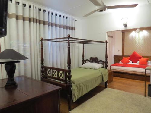 a bedroom with a four poster bed and a table at Dees Homestay Colombo in Colombo