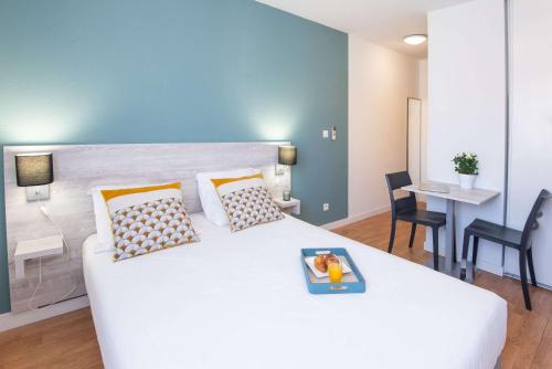 a bedroom with a large white bed and a table at Comfort Aparthotel Aix Le Tholonet in Aix-en-Provence