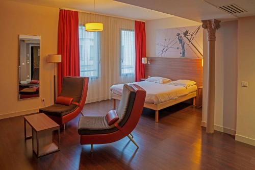 a hotel room with a bed and two chairs at Comfort Aparthotel Saint-Etienne in Saint-Étienne