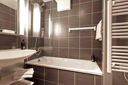 a bathroom with a bath tub and a sink at Comfort Aparthotel Saint-Etienne in Saint-Étienne