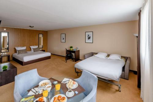 a hotel room with two beds and a table with food at Comfort Aparthotel Bordeaux Begles Arena in Bègles