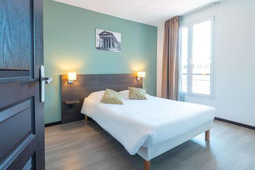 a bedroom with a white bed and a window at Comfort Aparthotel Nimes Centre in Nîmes