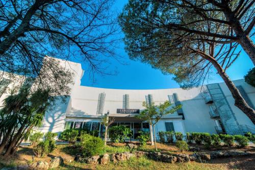 a building with trees in front of it at Comfort Aparthotel Frejus La Tour de Mare in Fréjus