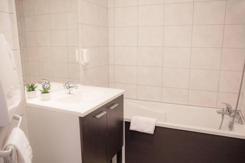 a white bathroom with a sink and a bath tub at Comfort Aparthotel Mutzig Portes d'Alsace in Mutzig