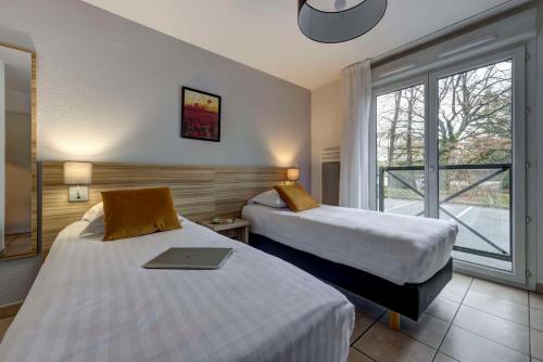 a hotel room with two beds with a laptop on it at Comfort Aparthotel Divonne L'Orée du Parc in Divonne-les-Bains