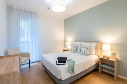 a bedroom with a white bed and a chair at Quality Aparthotel Nancy Zenith in Laxou