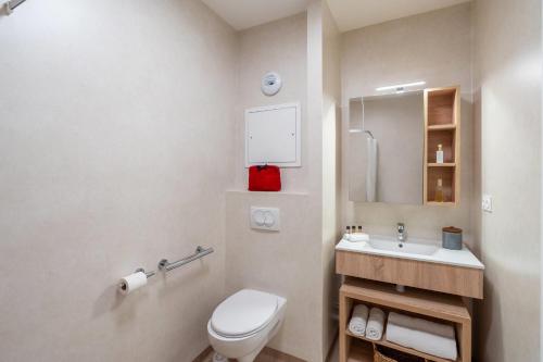 a bathroom with a white toilet and a sink at Quality Aparthotel Nancy Zenith in Laxou