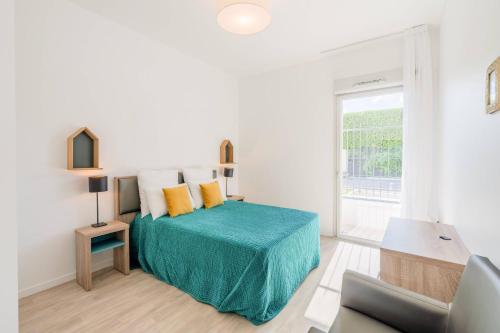 a white bedroom with a bed with a green blanket at Quality Aparthotel Parc Marne la Vallée in Bailly-Romainvilliers