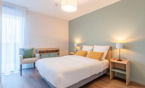 a bedroom with a white bed and a chair at Quality Aparthotel Moissy-Cramayel in Moissy-Cramayel