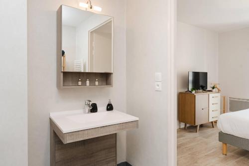 a bathroom with a sink and a mirror and a bed at Quality Aparthotel Dinan in Dinan