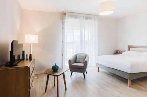 a bedroom with a bed and a chair and a television at Quality Aparthotel Dinan in Dinan