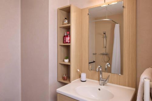 a bathroom with a sink and a shower at Quality Aparthotel Orleans Sud Zenith in Olivet