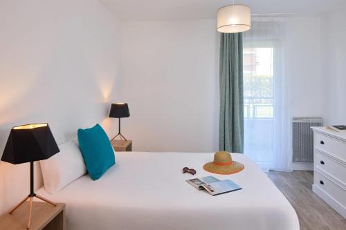 a bedroom with a white bed and a window at Quality Aparthotel Orleans Sud Zenith in Olivet
