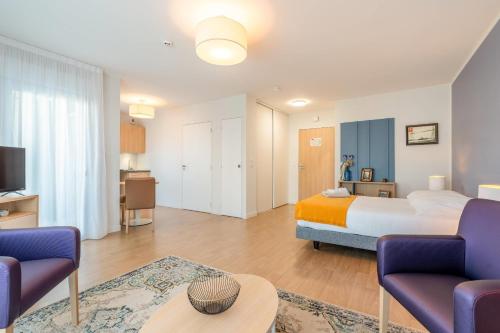 a bedroom with a bed and two chairs and a table at Quality Aparthotel Rochefort in Rochefort