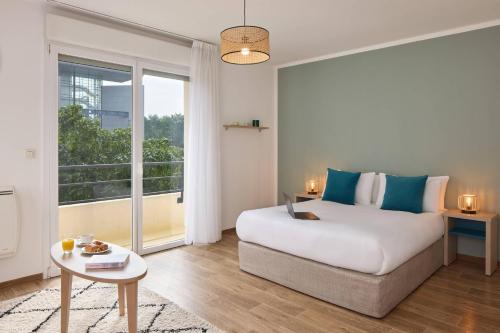 a bedroom with a bed and a table and a window at Quality Aparthotel Valenciennes in Valenciennes