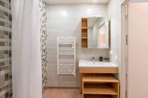 a bathroom with a sink and a mirror at Quality Aparthotel Villefontaine in Villefontaine