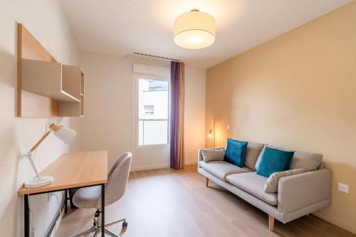 a living room with a couch and a desk at Quality Aparthotel Villefontaine in Villefontaine