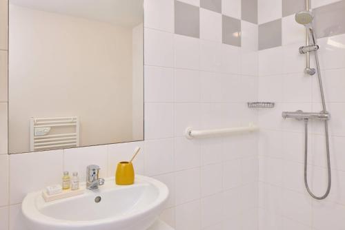 a white bathroom with a sink and a shower at Quality Aparthotel Portes de Rennes in Bruz