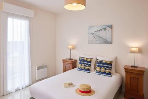 a bedroom with a white bed with a hat on it at Quality Aparthotel Portes de Rennes in Bruz