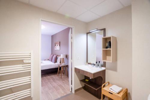a bathroom with a sink and a mirror and a bed at Quality Aparthotel Lyon L'Isle-d Abeau in LʼIsle-dʼAbeau