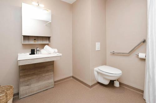 a bathroom with a white toilet and a sink at Quality Aparthotel Saint-Malo in Saint Malo