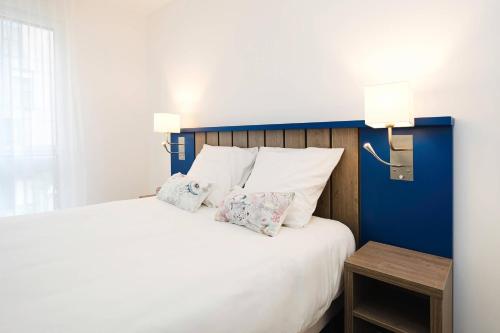 a bedroom with a large bed with two pillows at Quality Aparthotel Saint-Malo in Saint Malo