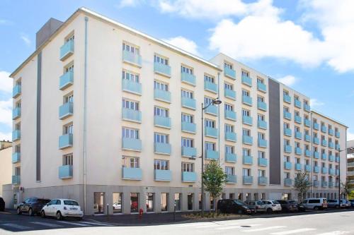a large white building with cars parked in a parking lot at Quality Aparthotel Reims - Saint-Thomas in Reims