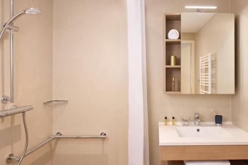 a bathroom with a sink and a shower and a mirror at Quality Aparthotel Morangis Orly in Morangis