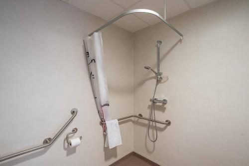 a bathroom with a shower with a white towel at Quality Aparthotel Bourgoin-Jallieu in Bourgoin