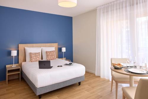 a bedroom with a bed with a laptop on it at Quality Aparthotel Voiron in Voiron