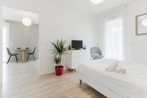 a white bedroom with a bed and a table and chairs at Quality Aparthotel St-Berthevin Laval in Saint-Berthevin-sur-Vicoin